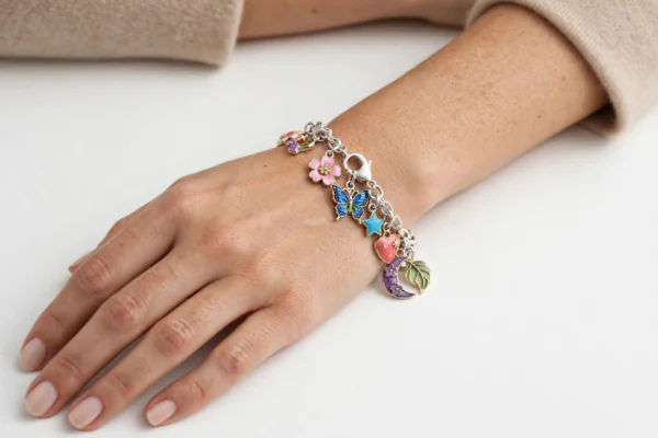 Elegant silver charm bracelet with colourful charms worn on a woman's wrist