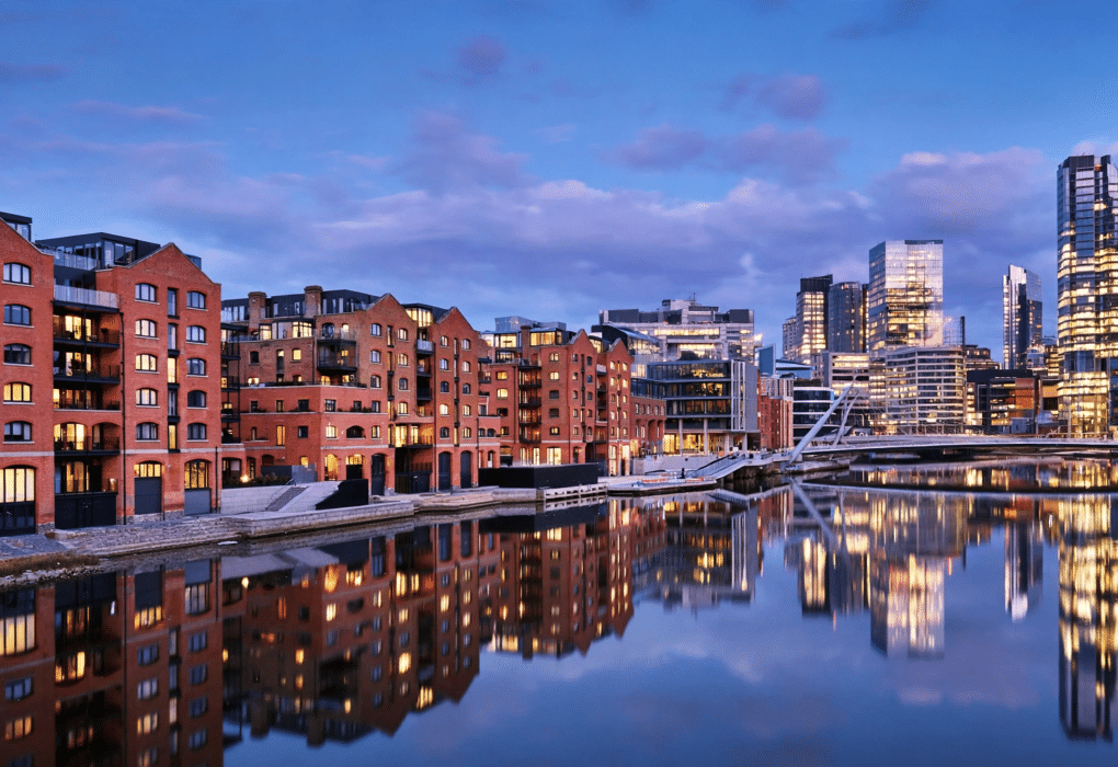 Modern UK city skyline at dusk with riverside apartment buildings, representing the best UK cities for property investment in 2026