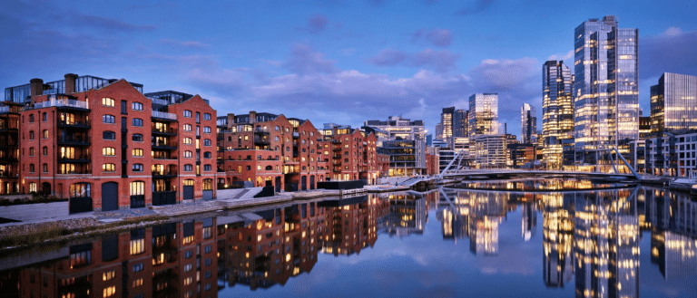 Modern UK city skyline at dusk with riverside apartment buildings, representing the best UK cities for property investment in 2026