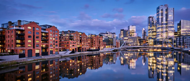 Modern UK city skyline at dusk with riverside apartment buildings, representing the best UK cities for property investment in 2026